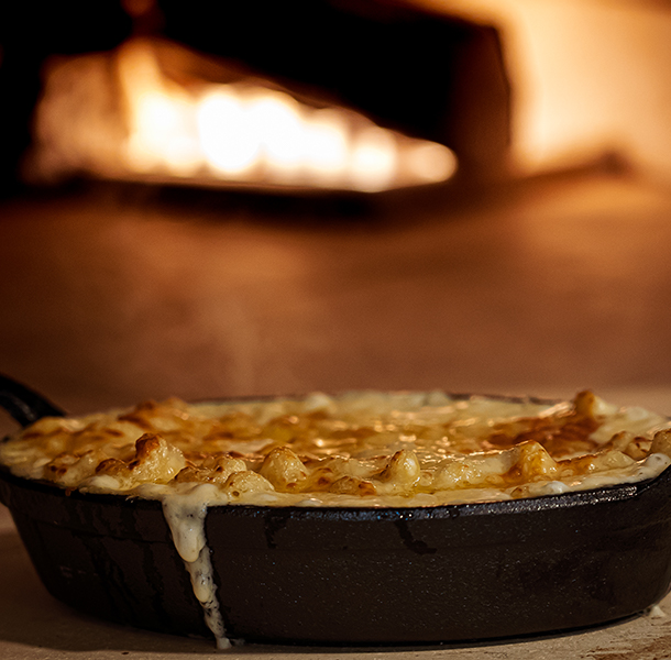 mac and cheese dish next to a wood-burning oven at walker's exchange restaurant